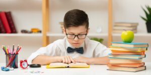 一個戴著領結、戴著眼鏡的小男孩正聚精會神地看書的照片，有效地代表了正在閱讀一篇科學論文