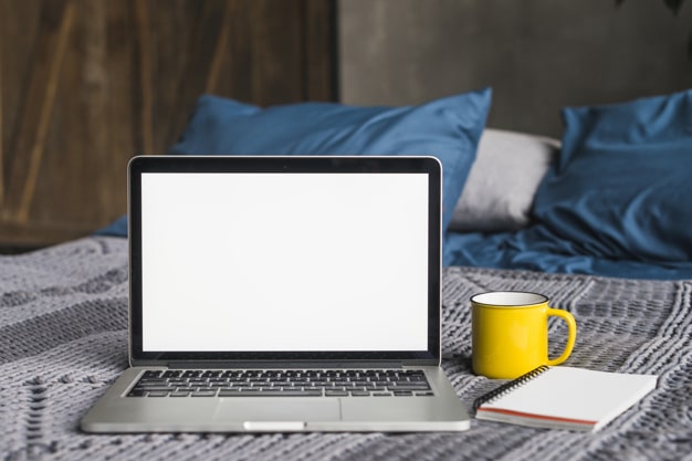 床上的電腦和咖啡象征著在家工作