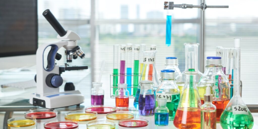 帶有顯微鏡的實驗室長凳和燒瓶和測試管中的許多不同彩色試劑，代表執行成功實驗的人
